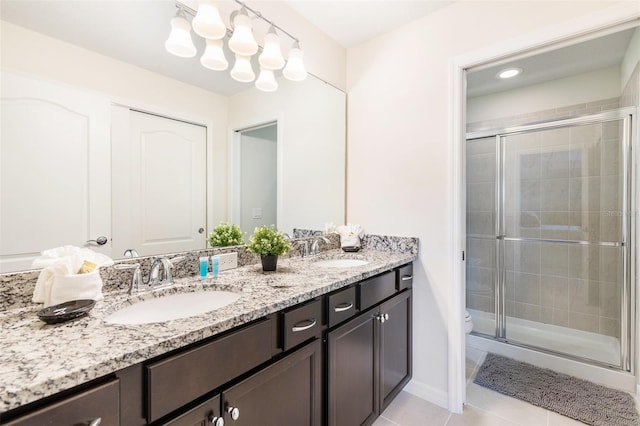 bathroom with a shower with door, toilet, vanity, and tile patterned flooring