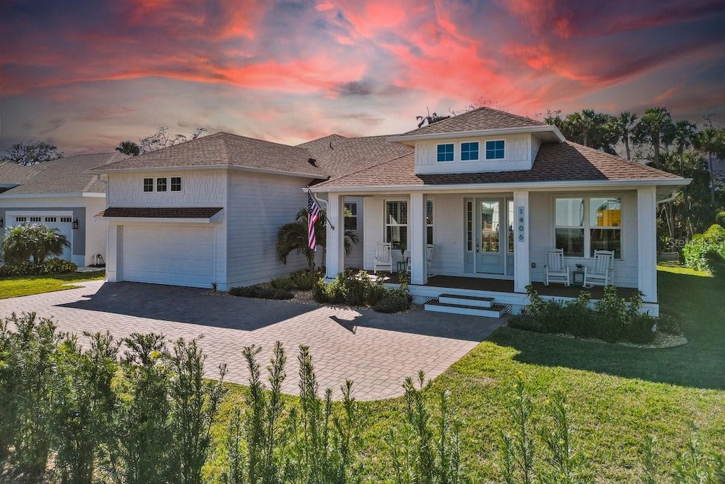 view of front of house featuring a yard, a porch, and a garage