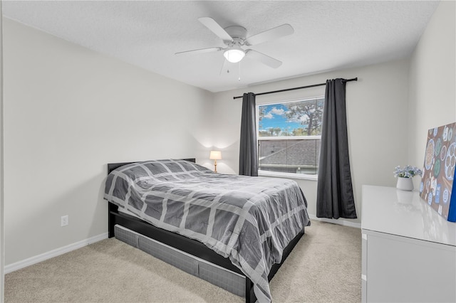 bedroom with ceiling fan, a textured ceiling, and light carpet