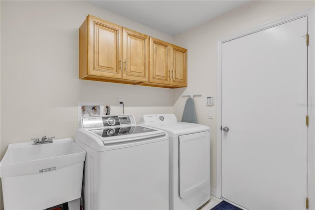 washroom featuring cabinets, sink, and independent washer and dryer