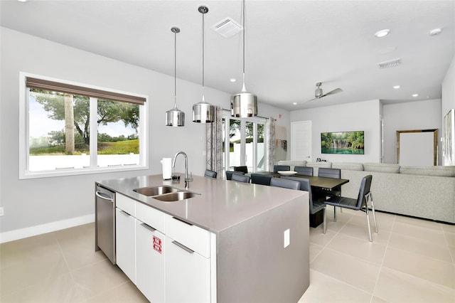 kitchen featuring sink, light tile patterned floors, dishwasher, an island with sink, and white cabinets