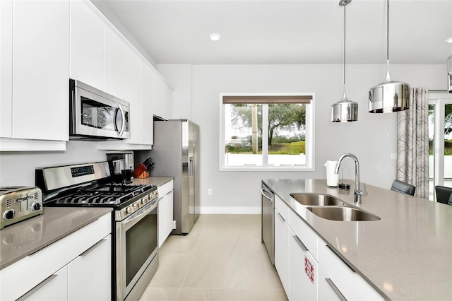 kitchen featuring sink, white cabinetry, hanging light fixtures, stainless steel appliances, and light tile patterned flooring