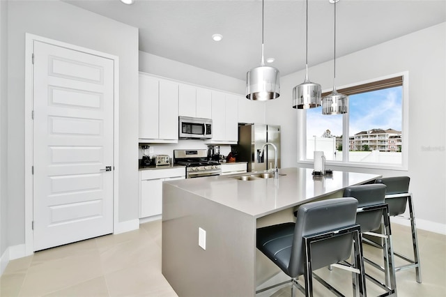 kitchen featuring an island with sink, white cabinets, a kitchen breakfast bar, hanging light fixtures, and stainless steel appliances