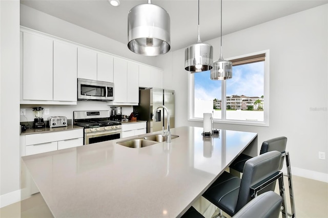 kitchen featuring sink, a breakfast bar, appliances with stainless steel finishes, an island with sink, and white cabinets