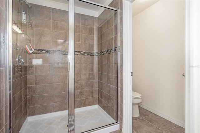 bathroom featuring tile patterned flooring, a shower with door, and toilet