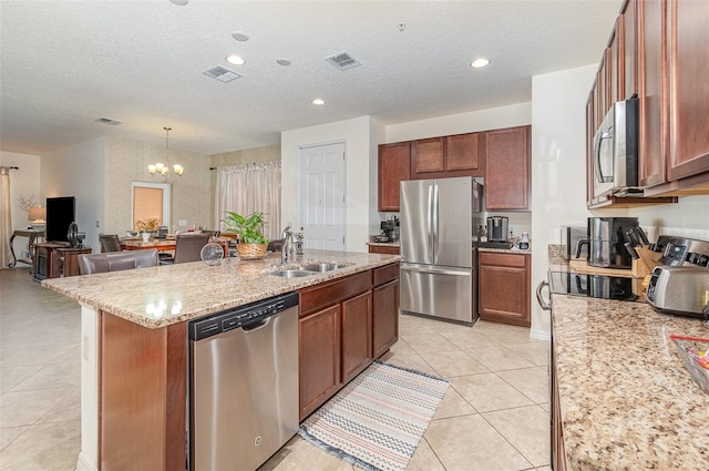 kitchen featuring sink, light tile patterned floors, appliances with stainless steel finishes, a textured ceiling, and a center island with sink