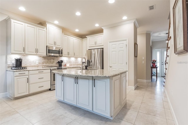 kitchen with light stone countertops, white cabinetry, sink, an island with sink, and stainless steel appliances