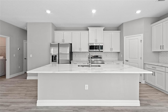 kitchen with sink, white cabinets, a kitchen island with sink, and appliances with stainless steel finishes