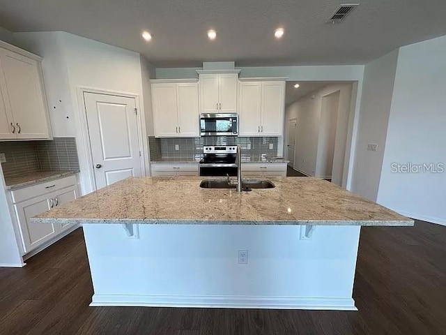 kitchen with a kitchen bar, white cabinetry, stainless steel appliances, and a kitchen island with sink