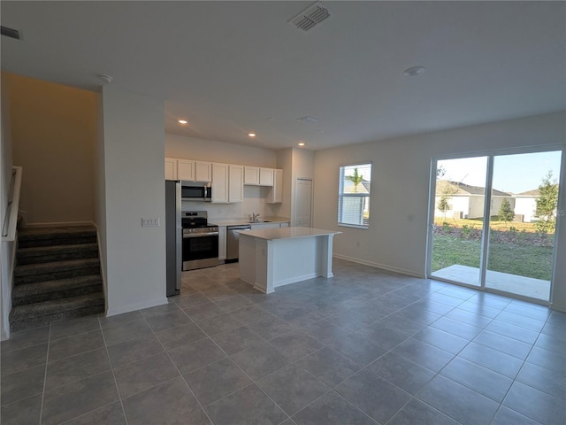 kitchen with white cabinetry, stainless steel appliances, tile patterned floors, a kitchen island, and sink