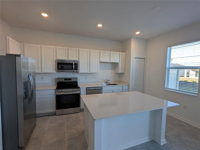 kitchen featuring white cabinets, sink, stainless steel appliances, and a kitchen island