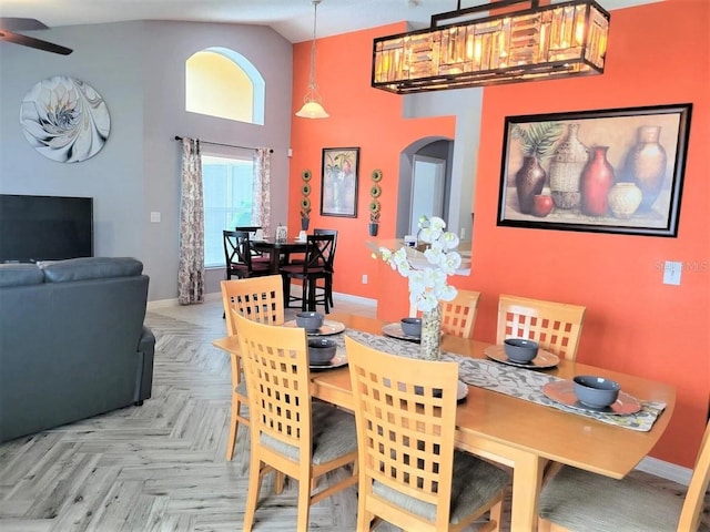 dining space featuring high vaulted ceiling and light parquet flooring