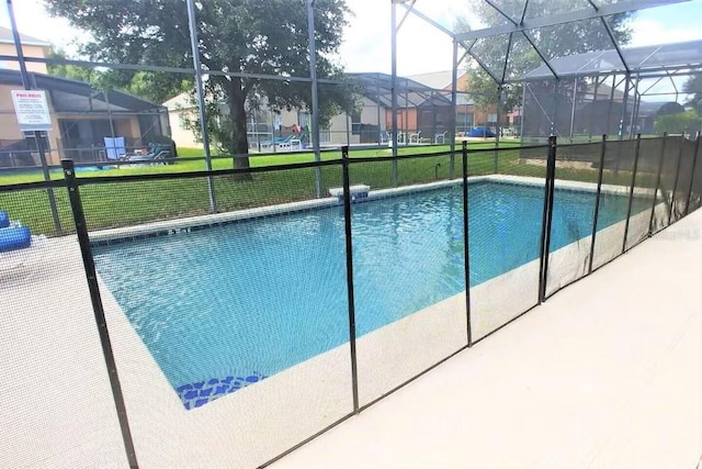 view of swimming pool featuring a lanai and a lawn