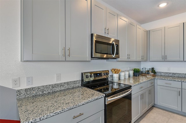 kitchen with light stone counters, gray cabinets, and stainless steel appliances