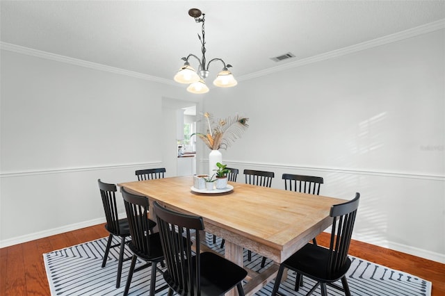 dining room with an inviting chandelier, ornamental molding, and hardwood / wood-style floors