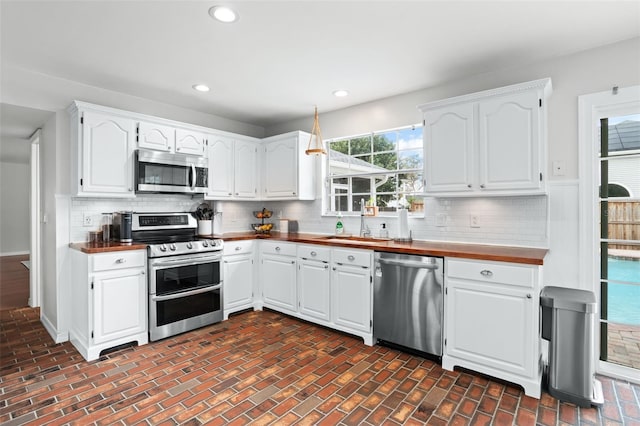 kitchen with decorative backsplash, sink, stainless steel appliances, and white cabinetry