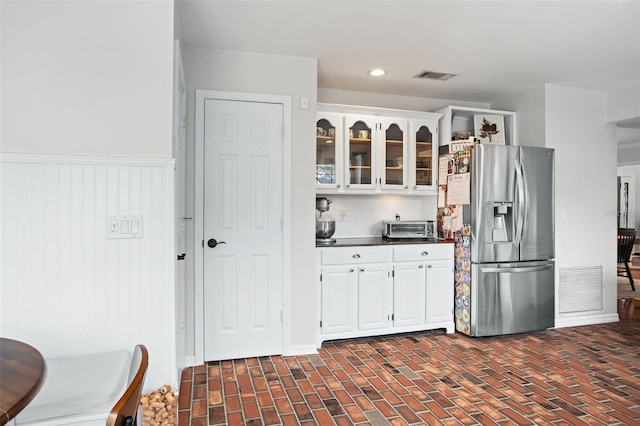 kitchen featuring stainless steel refrigerator with ice dispenser and white cabinetry