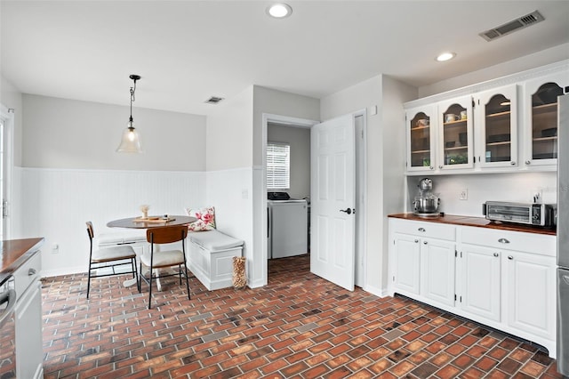 kitchen with decorative light fixtures, dishwasher, white cabinets, and washer / dryer