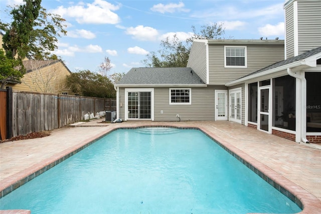 view of pool with central AC, french doors, a patio area, and a sunroom