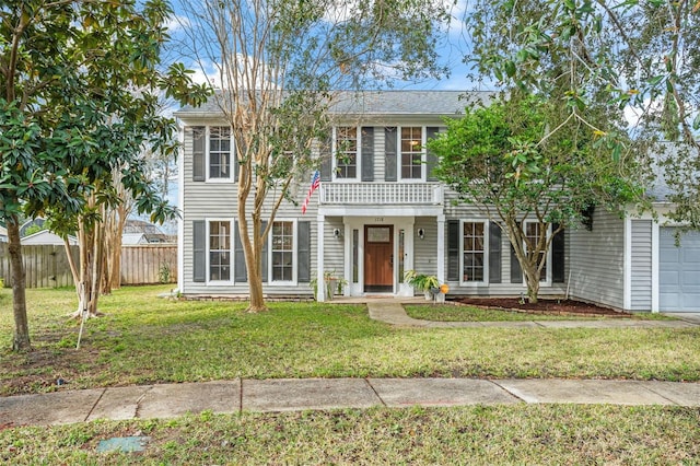 colonial home featuring a balcony, a garage, and a front yard