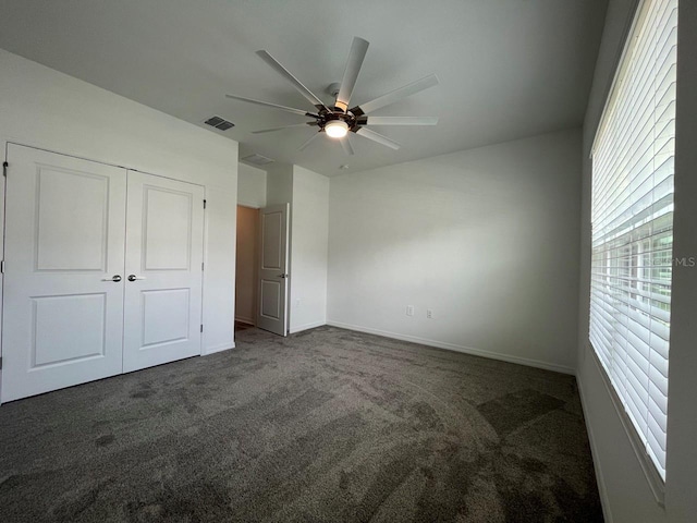 unfurnished bedroom featuring ceiling fan, a closet, and dark carpet