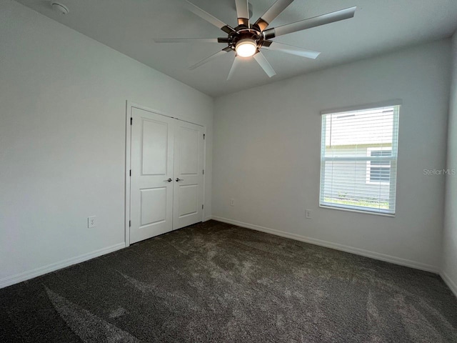 unfurnished bedroom featuring ceiling fan, a closet, and dark colored carpet