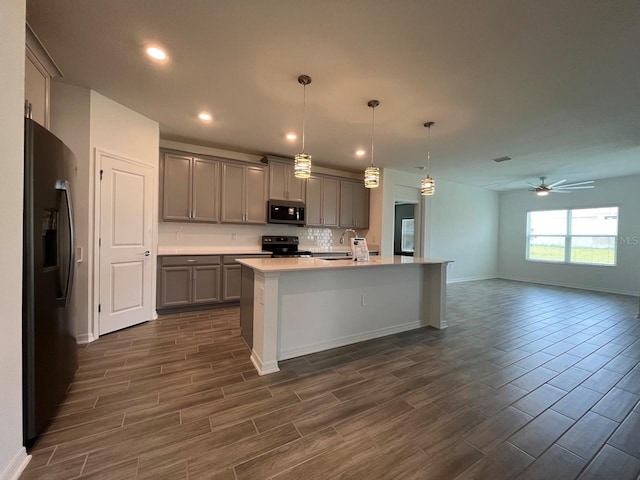 kitchen featuring black appliances, sink, hanging light fixtures, gray cabinets, and a center island with sink