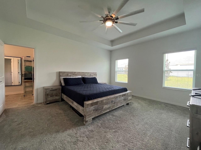 carpeted bedroom featuring a raised ceiling and ceiling fan