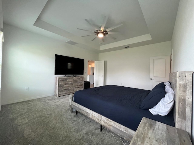 bedroom with ceiling fan, a tray ceiling, and carpet flooring