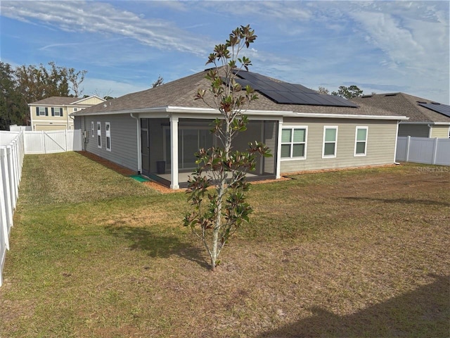 rear view of house featuring a lawn, a sunroom, and solar panels