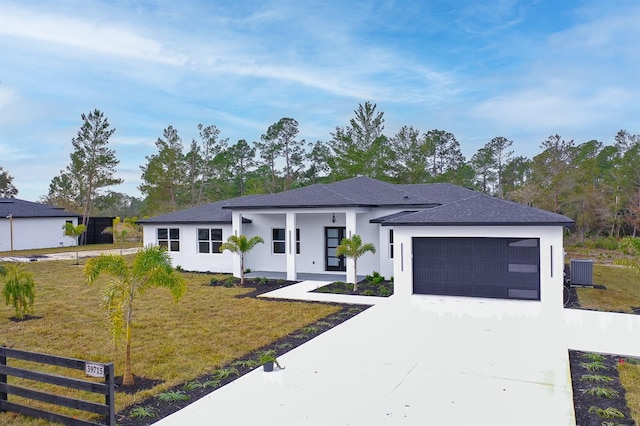 view of front of home featuring a garage, a front lawn, and central air condition unit