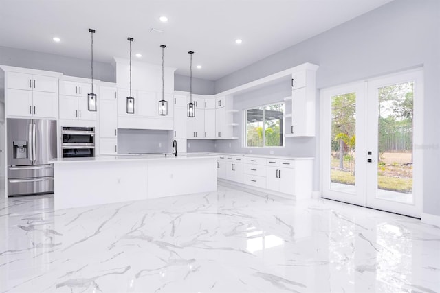 kitchen featuring stainless steel appliances, pendant lighting, a center island with sink, and white cabinets