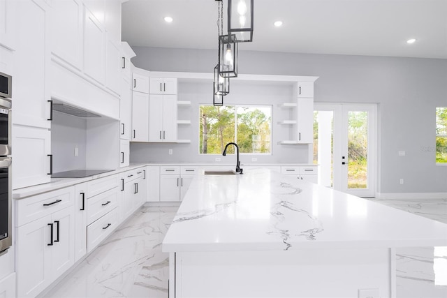 kitchen with sink, white cabinetry, a spacious island, light stone counters, and decorative light fixtures