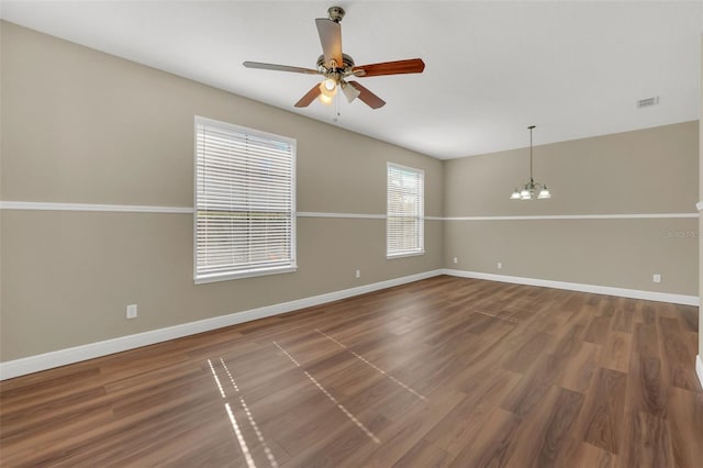 spare room featuring ceiling fan with notable chandelier and dark hardwood / wood-style floors