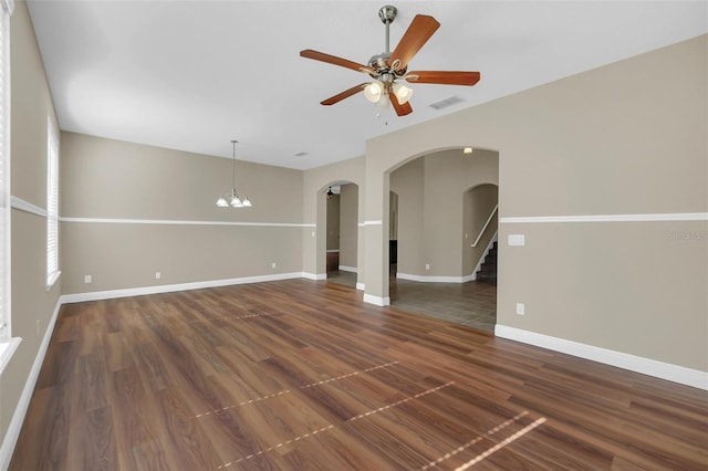 unfurnished room featuring ceiling fan with notable chandelier and dark hardwood / wood-style floors