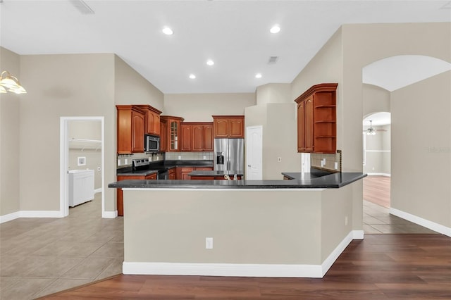 kitchen with stainless steel appliances, tile patterned floors, kitchen peninsula, and tasteful backsplash