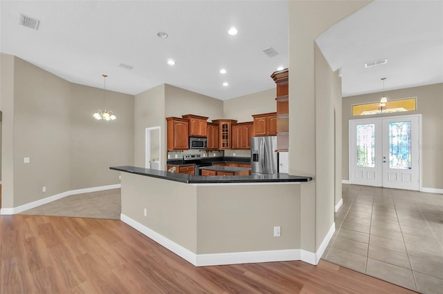 kitchen with decorative light fixtures, kitchen peninsula, french doors, and stainless steel appliances