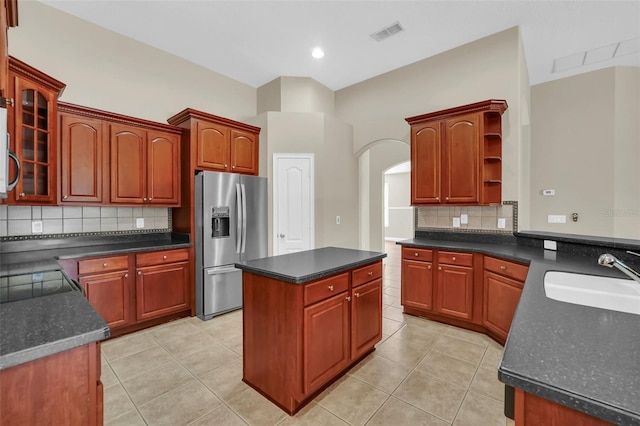 kitchen with tasteful backsplash, a center island, sink, stainless steel fridge with ice dispenser, and light tile patterned floors