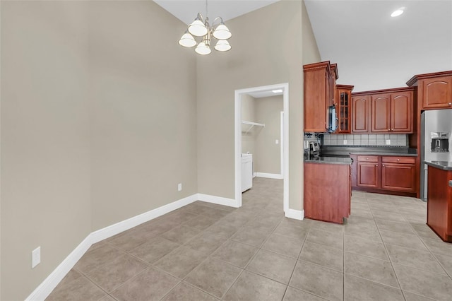 kitchen featuring appliances with stainless steel finishes, tasteful backsplash, a notable chandelier, high vaulted ceiling, and light tile patterned floors