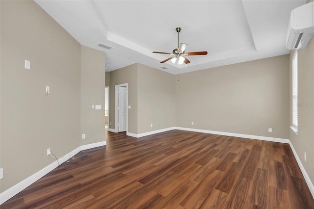 spare room featuring a raised ceiling, a wall mounted AC, dark hardwood / wood-style flooring, and ceiling fan