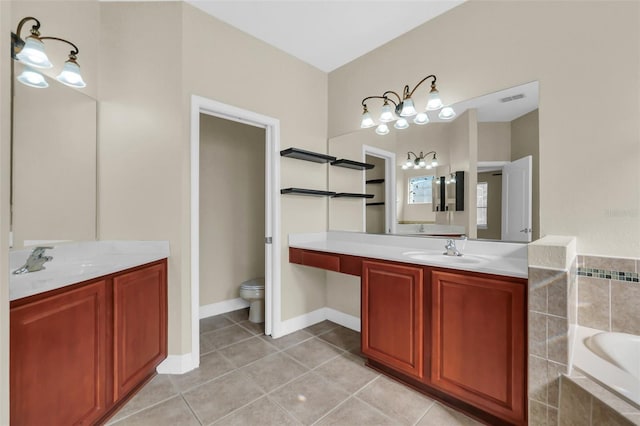 bathroom featuring tiled tub, toilet, vanity, and tile patterned flooring