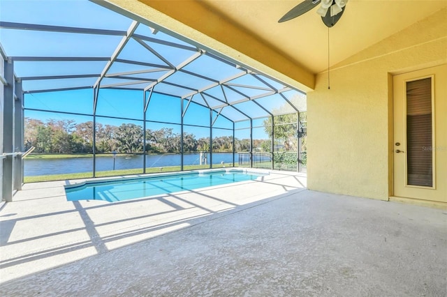 view of pool with glass enclosure, ceiling fan, a water view, and a patio