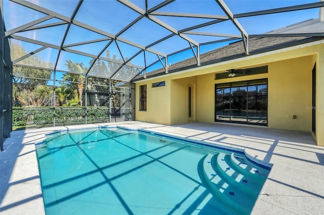 view of swimming pool with ceiling fan, glass enclosure, and a patio area