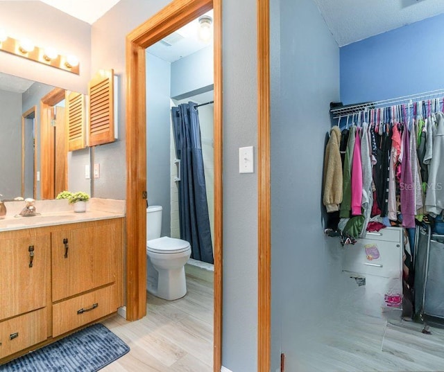 bathroom featuring toilet, walk in shower, wood-type flooring, and vanity