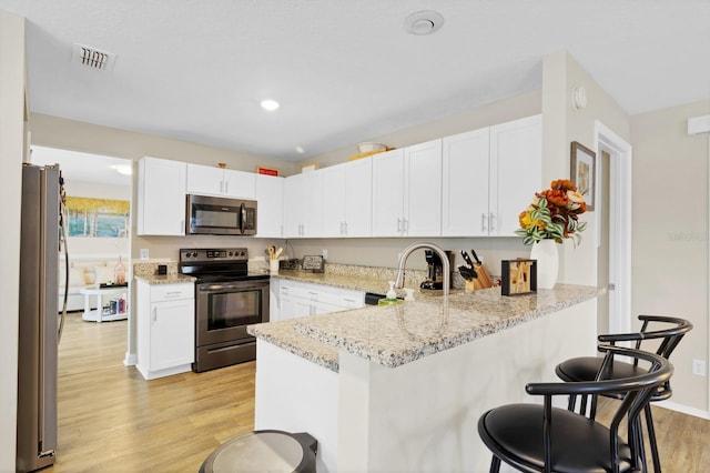 kitchen featuring appliances with stainless steel finishes, white cabinets, and kitchen peninsula