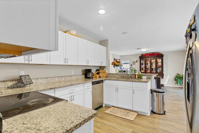 kitchen with kitchen peninsula, appliances with stainless steel finishes, light wood-type flooring, white cabinets, and sink