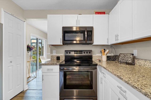 kitchen featuring light stone counters, white cabinetry, dark hardwood / wood-style floors, and stainless steel appliances