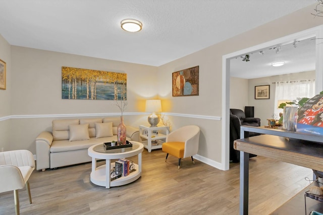 living room with a textured ceiling, track lighting, and hardwood / wood-style flooring