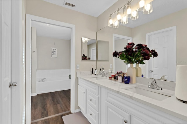 bathroom featuring vanity, a washtub, and hardwood / wood-style flooring