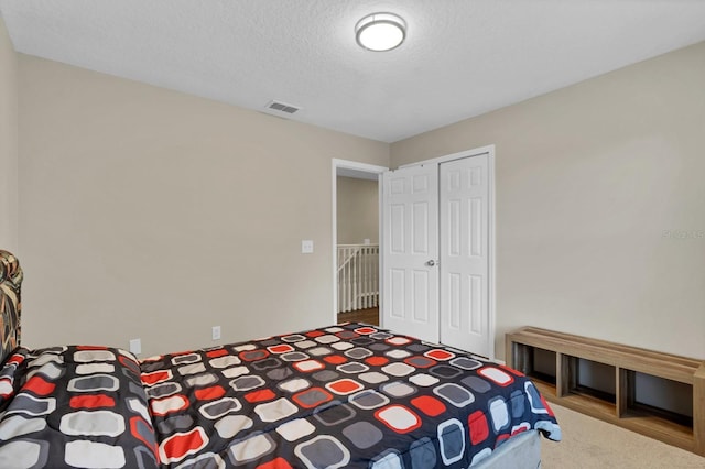 carpeted bedroom with a closet and a textured ceiling